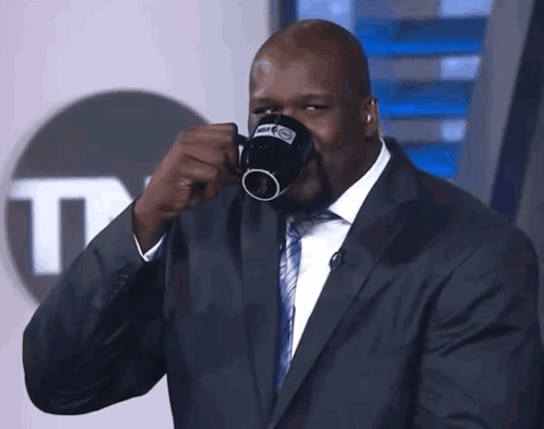 a man in a suit is drinking from a mug that says nba|833x657.3674698795181